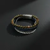 Pulsera de hombre con tres hilos: uno de cuentas de piedra verde y marrón, uno de cuero trenzado azul marino y uno de cadena plateada.