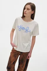 Remera color crudo de algodón lavado con cuello redondo, manga corta y calce oversized. Estampado frontal con dos flores abstractas en color celeste.