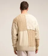 Cardigan de punto beige con diferentes texturas y bloques de color. Tiene cuello en V, abotonadura frontal y mangas largas.