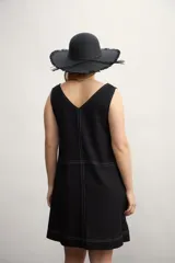 Vestido corto color negro, sin mangas, con escote en V y bolsillos laterales.