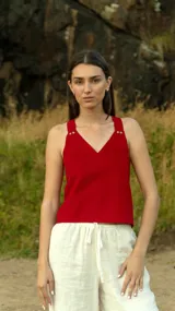 Chaleco rojo con escote en V y tirantes gruesos con botones dorados.