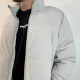Campera puffer color beige con cierre frontal y cuello alto. Diseño acolchado con bolsillos laterales.