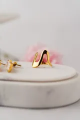 Anillo dorado con diseño ondulado y minimalista, fabricado en acero quirúrgico con baño de oro.