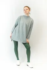 Sweater negro de tejido texturizado, con cuello alto, mangas 3/4 y corte asimétrico con aberturas laterales.