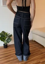 Pantalón de jean azul oscuro de corte ancho con dobladillo en color gris claro.