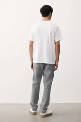 Jean gris de cinco bolsillos en denim de algodón elástico con cintura estándar y cierre con botón. Piernas rectas con buena libertad de movimiento en muslo y rodilla.