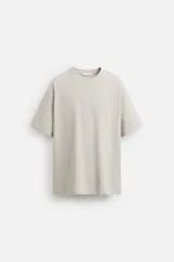 Camiseta relaxed fit confeccionada en algodón compacto, color gris claro. Cuello redondo y manga corta.