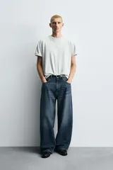 Pantalón de jeans de algodón, corte baggy fit, tiro medio, con efecto lavado en tonos grises y verdes. Presenta cinco bolsillos y cierre frontal con cremallera y botón.