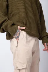 Pantalón cargo color beige con bolsillos laterales con solapa y botón. Corte ajustado.