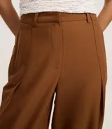 Pantalón recto color marrón confeccionado en cupro, con trabillas en la cintura, cierre tradicional y superposición lateral.