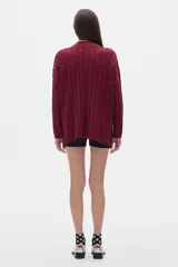Sweater tejido color borgoña con cuello alto, corte oversize y mangas largas con detalle de trenzas verticales.