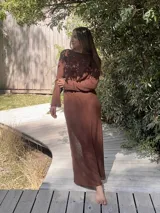 Vestido largo marrón de tejido de algodón fino y ligero, con mangas largas y escote redondo. Puede usarse con el escote hacia adelante o hacia atrás.