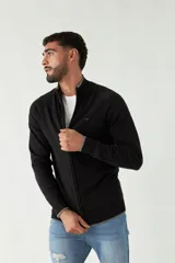 Campera tejida negra con cuello alto, cierre frontal y puños. Presenta logo bordado en el pecho.