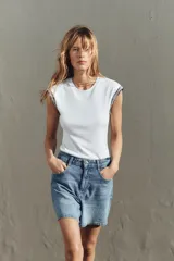Camiseta negra de cuello redondo y sisa con detalle de fornitura con hilo metalizado a contraste en las mangas.
