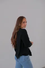 Sweater negro de punto con cuello redondo y corte recto. Presenta detalle de botones grandes en el hombro.