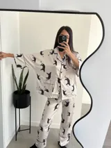 Conjunto de pijama blanco con estampado de tigres negros, ribetes negros, camisa de manga larga con botones y pantalón largo.