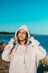 Buzo hoodie rosa con capucha y cordones ajustables. Estampado en la espalda con el texto "ClassyWaves Surf Company" y un logo de una ola.