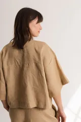 Blusa color crema confeccionada en lino, con mangas cortas, escote en V y lazos frontales.