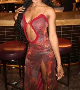 Vestido corto con estampado abstracto en tonos rojizos y marrones, con escote pronunciado en forma de cerradura y ribete de volantes rojos.