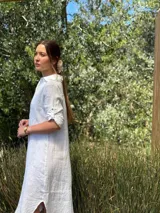 Vestido camisero largo de lino blanco, con corte en la cintura, abertura lateral y botones de nácar.