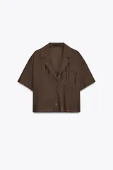 Camisa marrón de cuello solapa y escote pico con manga corta. Bolsillos de plastrón en pecho. Cierre frontal con botones.