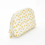Neceser de tela color beige con estampado de limones amarillos y hojas verdes. Tiene forma ovalada y cierre superior con cremallera.