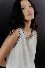 Chaleco de tejido color crudo con pespuntes negros en cuello y sisas.