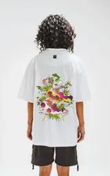 Remera blanca de corte oversize con estampado de moléculas y hojas de marihuana.