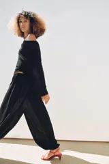 Top negro de escote asimétrico con una manga corta y una manga larga. Tiene detalle de frunces laterales y bajo asimétrico.