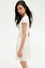 Vestido corto de crepé de viscosa con estampado floral, escote en V y manga japonesa. Tiene frente cruzado con tiras para atar, cuerpo entallado y falda con leve vuelo.