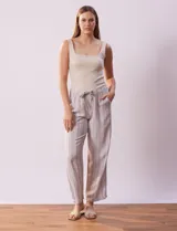 Pantalón largo de lino y rayón a rayas verticales grises y blancas. Tiene pretina elastizada con lazo de ajuste, bolsillos delanteros y traseros.