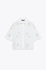 Camisa blanca de mangas cortas con bordado de flores rosas y celestes.