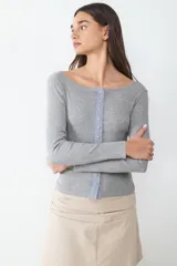 Camiseta de manga larga gris con cuello redondo amplio y cierre frontal de botones celestes a contraste.