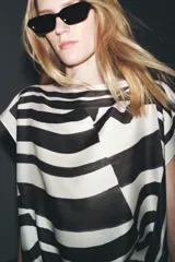 Top de Zara Woman Collection, con estampado abstracto en blanco y negro, cuello barco, mangas caídas y bajo ajustable con lazadas.