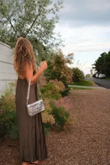 Bandolera plateada con textura arrugada, múltiples compartimentos internos y doble correa.