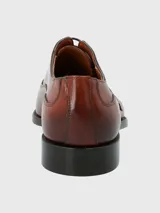 Zapato formal de cuero color marrón con punta alargada y cordones.