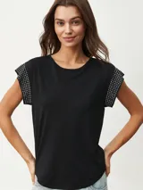 Remera negra de corte clásico con mangas cortas y detalle de tachas plateadas en los hombros.