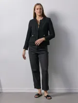 Chaqueta negra en tejido tweed de la marca Nanette. Tiene escote mao, abertura central y bolsillos delanteros. Los puños tienen apliques de botones perlados y la terminación es desflecada. Tiene forro interno.