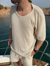 Buzo de punto color beige, de manga corta y cuello redondo.