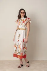 Vestido midi camisero de algodón color natural con estampado de flores, animales y ramas en tonos rojo, marrón, verde y azul. Tiene cuello mao, mangas cortas con volados, bolsillos laterales y cinturón de soga color beige.