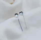 Aros colgantes plateados con forma de círculo en la parte superior y barra vertical delgada en la parte inferior.