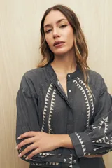 Camisa gris oscuro con estampado de triángulos blancos en el frente, mangas y cuello.