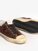 Zapatillas bajas marrones de gamuza con cordones negros, suela color crema con línea celeste y detalle de estrella calada en el lateral.