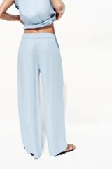 Pantalón celeste de tiro alto con cintura elástica, bolsillos delanteros y pernera ancha.