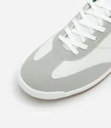 Championes deportivos de cuero color blanco con detalles en gris y verde.