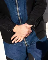 Camisa de denim negro y azul con cortes curvos y simétricos, cierre frontal de alpaca, cuello en cuero vacuno y bolsillos delanteros con bordado del logo Temblad.