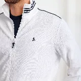 Campera blanca con cierre frontal, cuello mao y bolsillos laterales con ribete azul marino. Presenta puños y cintura acanalados con rayas horizontales en azul marino y blanco. Logo de pingüino bordado en el pecho.