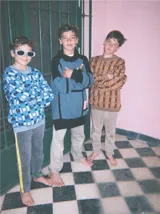 Pantalón de jean celeste con efecto lavado, corte recto y largo a la rodilla. Presenta una cinta vertical color violeta en la pierna izquierda, una cinta vertical color verde en la pierna derecha y una cinta horizontal color rosa en la parte inferior de ambas piernas.