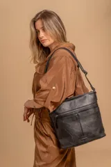 Cartera tipo bandolera de tamaño mediano confeccionada en símil cuero color marrón. Presenta una correa larga regulable, dos compartimientos principales y un bolsillo frontal con cierre de cremallera.