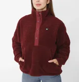 Buzo polar gris de mujer con cuello alto abotonado y bolsillo tipo canguro. Tiene un parche redondo con el logo de Cat en el lado izquierdo del pecho y broches con el logo de Cat en la parte delantera.